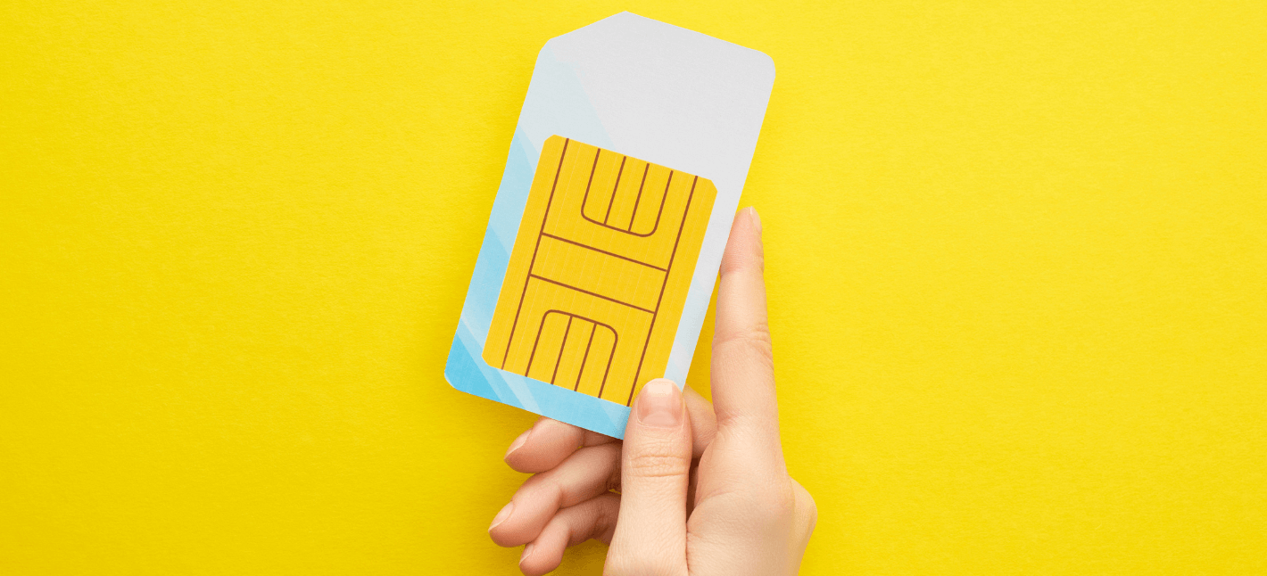 the image shows a hand holding a big IoT SIM card (M2M SIM card) on the yellow background